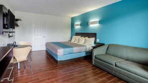 A hotel room with a bed, a sofa, a desk with a chair, and a TV. - Motel 6 Lexington, VA (Lexington)