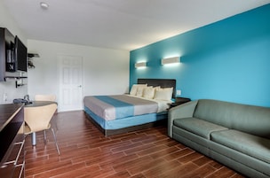Una habitación de hotel con cama, sofá, escritorio y silla, y televisor.