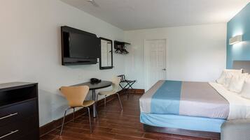 A hotel room with a bed, a desk with a chair, a television, and a wardrobe.
