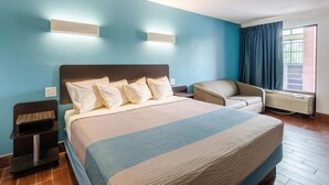 A hotel room with a large bed, a chair, a desk, and a window with curtains. - Motel 6 Lexington, VA (Lexington)