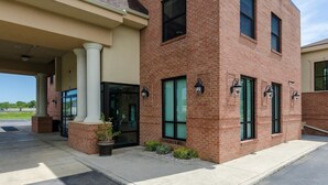 A two-story building with a brick facade, large windows, and a covered entrance area with columns. - Motel 6 Lexington, VA (Lexington)