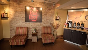 L'espace d'accueil d'un hôtel Red Roof Inn, avec deux fauteuils à rayures, un coin café et un mur en pierre en arrière-plan.
