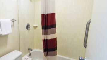 A bathroom with a bathtub, toilet, and shower curtain.