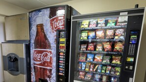 Un distributeur automatique orné d’une publicité pour Coca-Cola et proposant un assortiment de collations.
