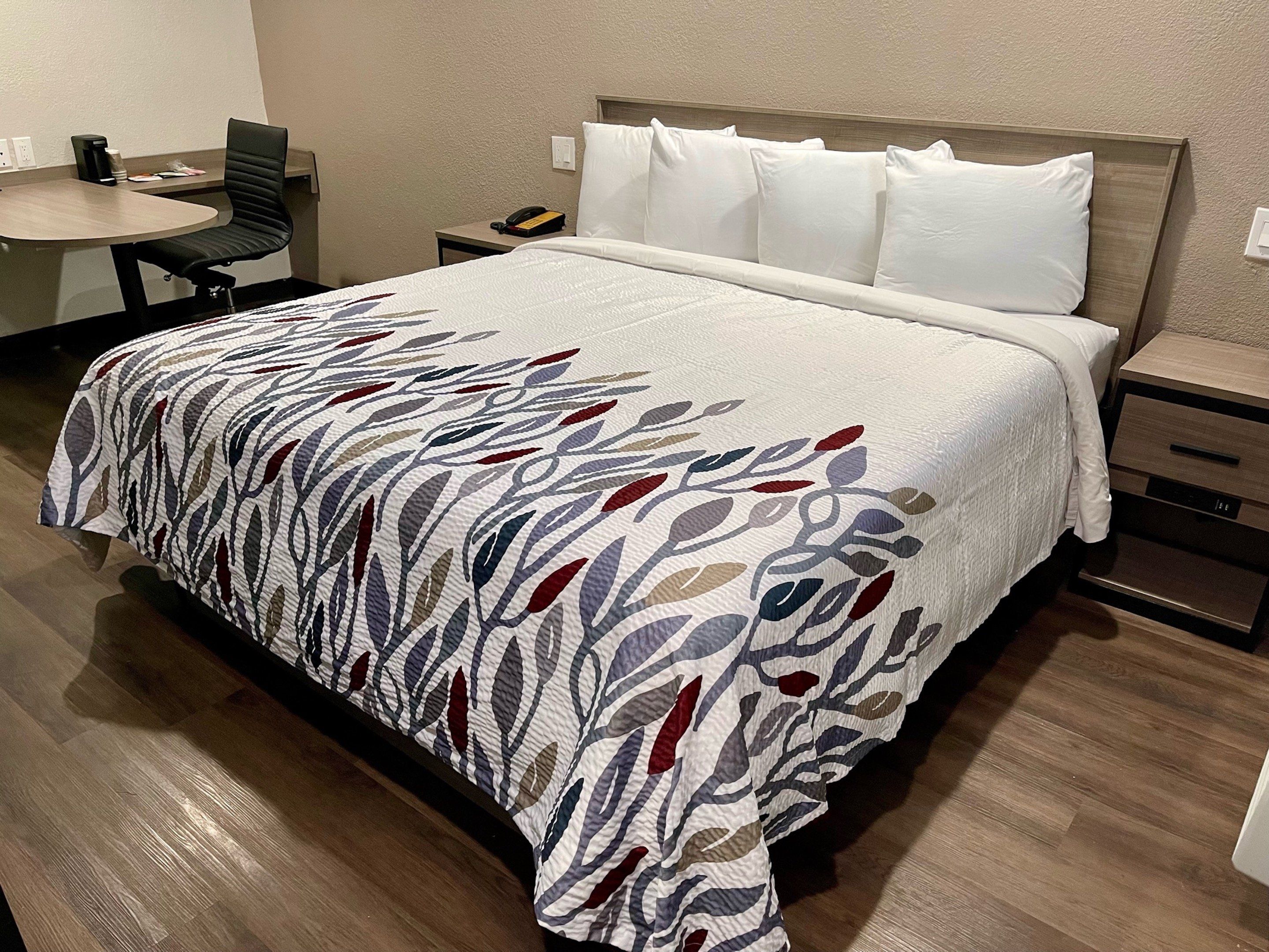 Una habitación de hotel con una cama, un escritorio y una silla.