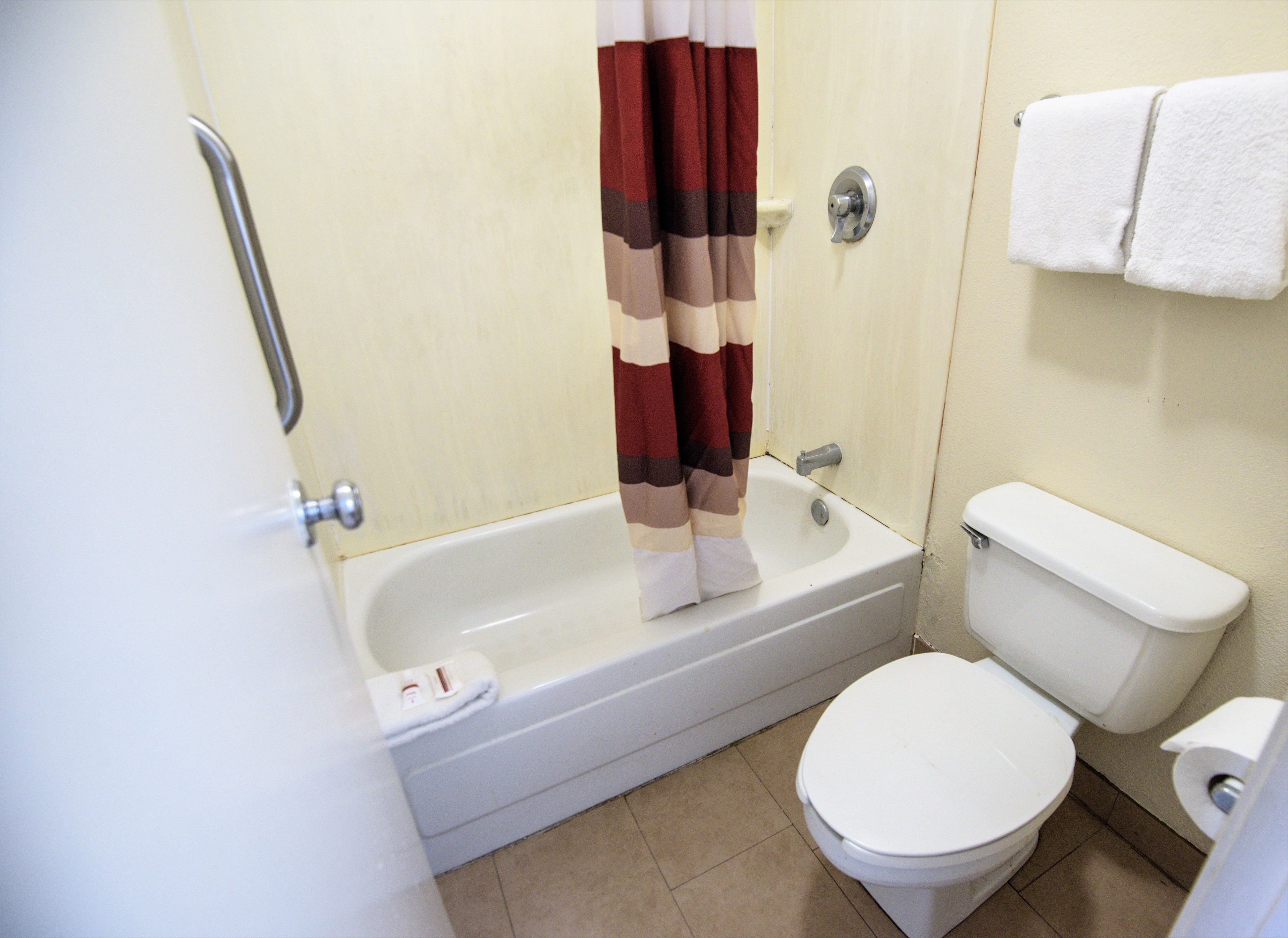 Une salle de bain avec une baignoire, des toilettes et un rideau de douche.