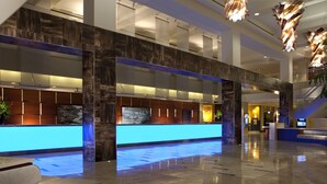 A spacious lobby with a reception desk, a staircase, and a large digital screen. - Hilton Orlando Lake Buena Vista - Disney Springs® Area (Lake Buena Vista)