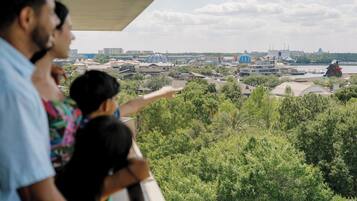 A balcony overlooking a cityscape with buildings, trees, and a large rock formation.