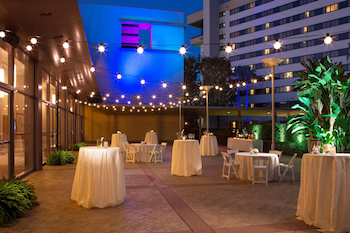 A hotel lobby with a checkered floor, wooden cabinets with wine and snacks, and a central counter with baskets. at Hilton Orlando Lake Buena Vista - Disney Springs® Area
