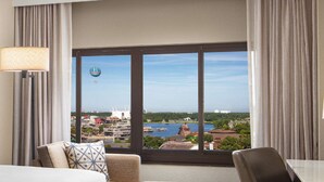 A hotel room with a large window offering a view of a cityscape, including a prominent white building and a body of water. - Hilton Orlando Lake Buena Vista - Disney Springs® Area (Lake Buena Vista)
