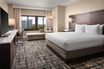 A hotel room with a large window offering a view of a cityscape, including a prominent white building and a body of water. at Hilton Orlando Lake Buena Vista - Disney Springs® Area