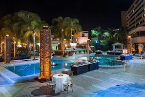 A pool area with multiple pools, lounge chairs, and a dining setup.