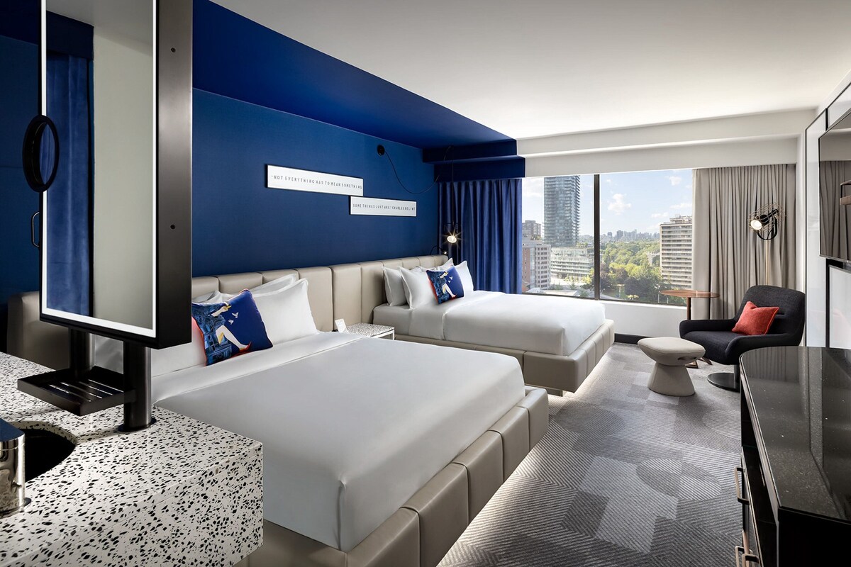 Una habitación de hotel con dos camas, un escritorio y vistas a la ciudad.