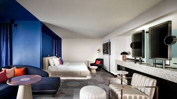Una habitación de hotel moderna con una cama, un sofá, una mesita de café, una silla y una pequeña mesa.
