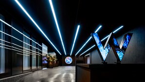 A modern interior with linear light fixtures, a circular digital display, and a reception area with a V-shaped design. - W Toronto (Toronto)