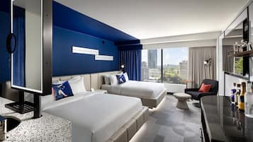 Una habitación de hotel moderna con dos camas, un escritorio y vistas a la ciudad.