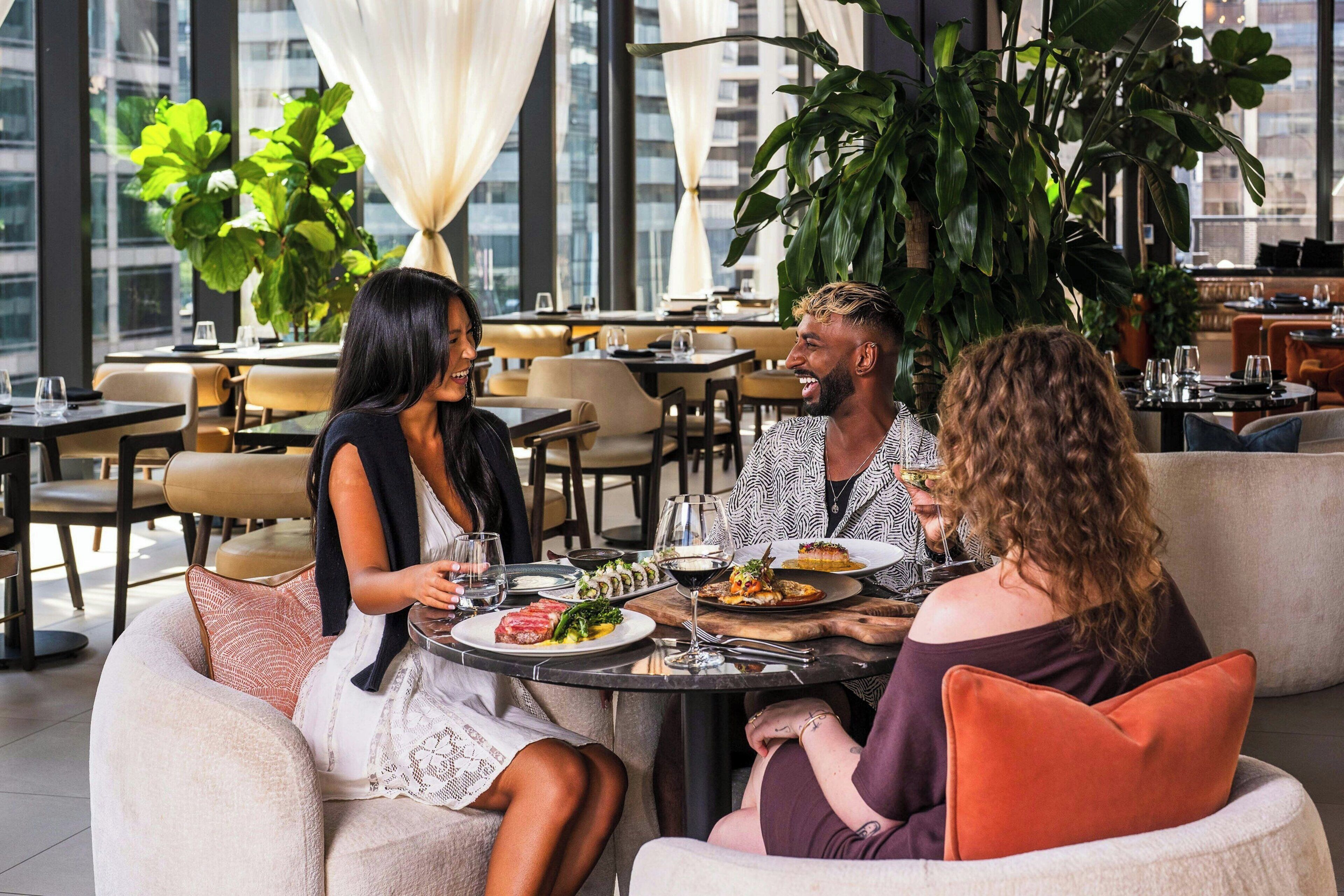 Un groupe de personnes est réuni dans un restaurant offrant une vue sur le paysage urbain.