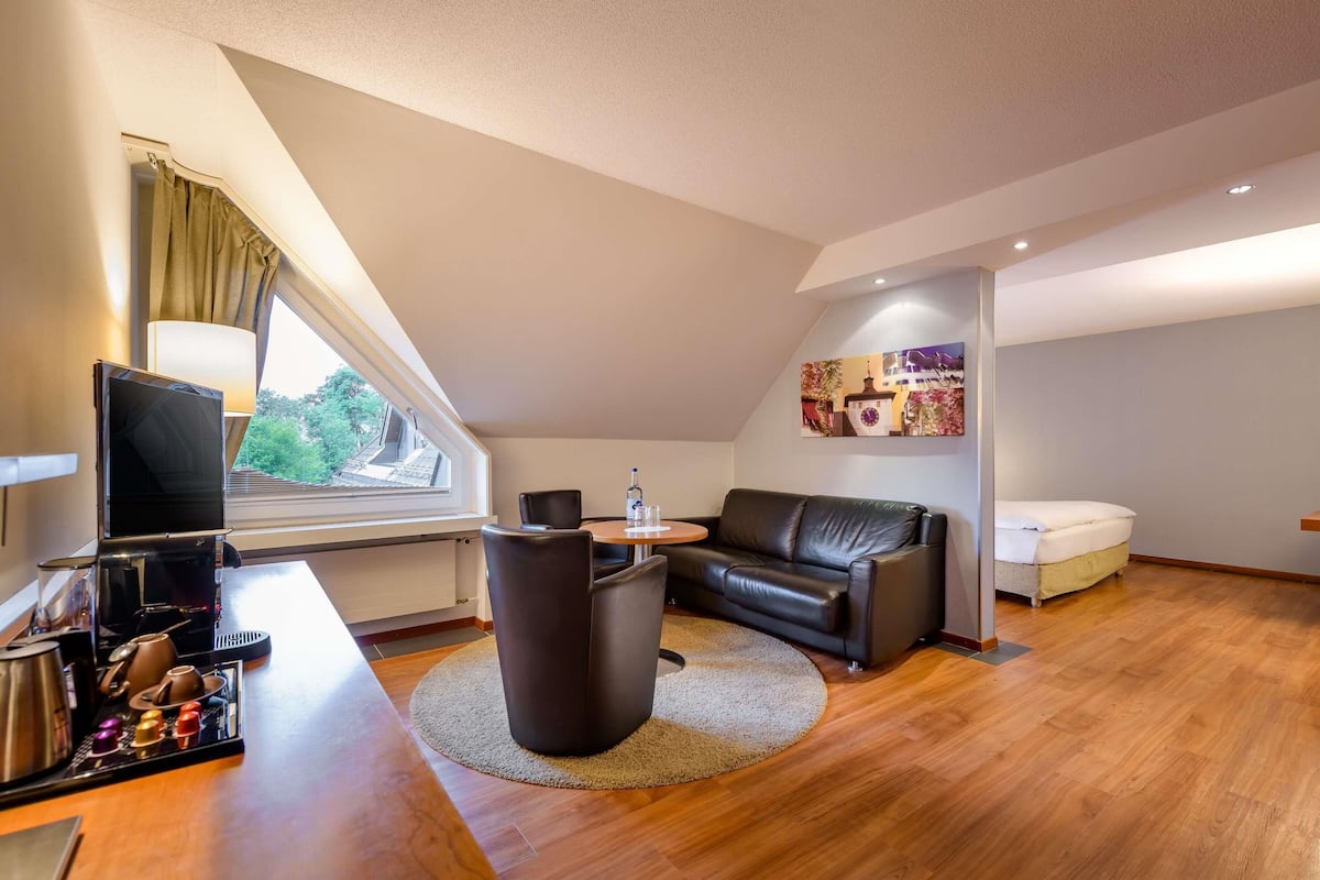 A modern living room with a sofa, a round table, a television, and a coffee machine.