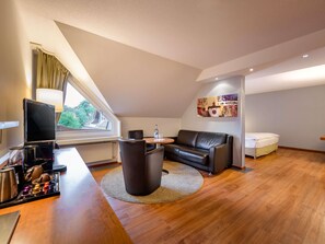 Una sala de estar moderna con un sofá, una mesa redonda, un televisor y una cafetera.