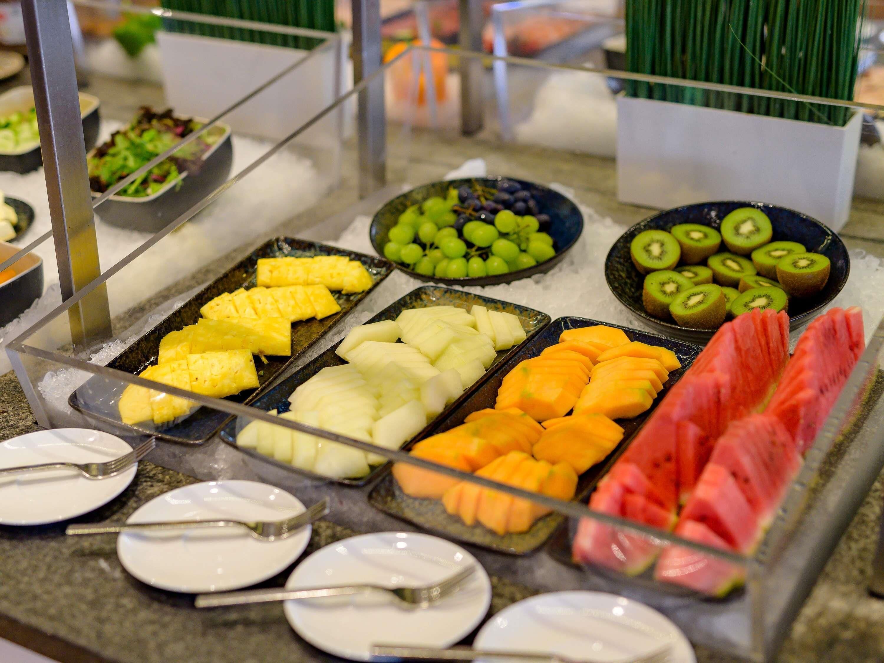 A buffet with various fruits and vegetables on trays.