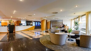 Un hall de hotel con mostrador de recepción, zona de estar y mostrador de check-in.