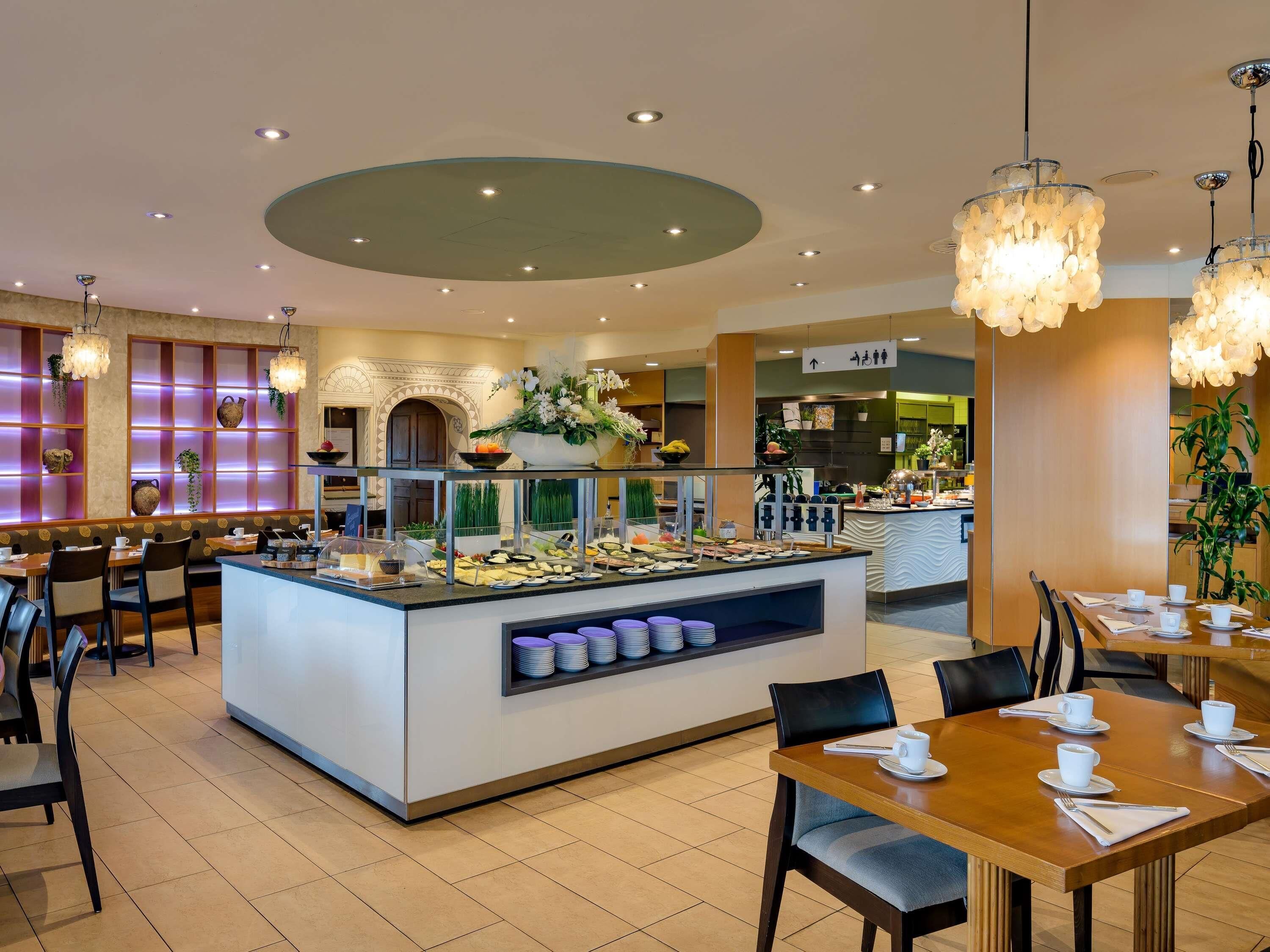A hotel dining area with a buffet, seating arrangements, and a central island with food displays.