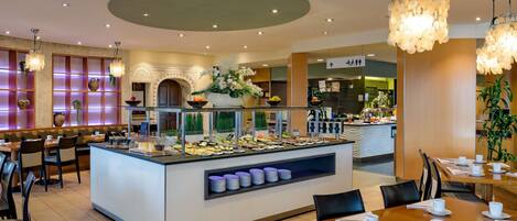 A hotel dining area with a buffet, seating arrangements, and a central island with food displays.