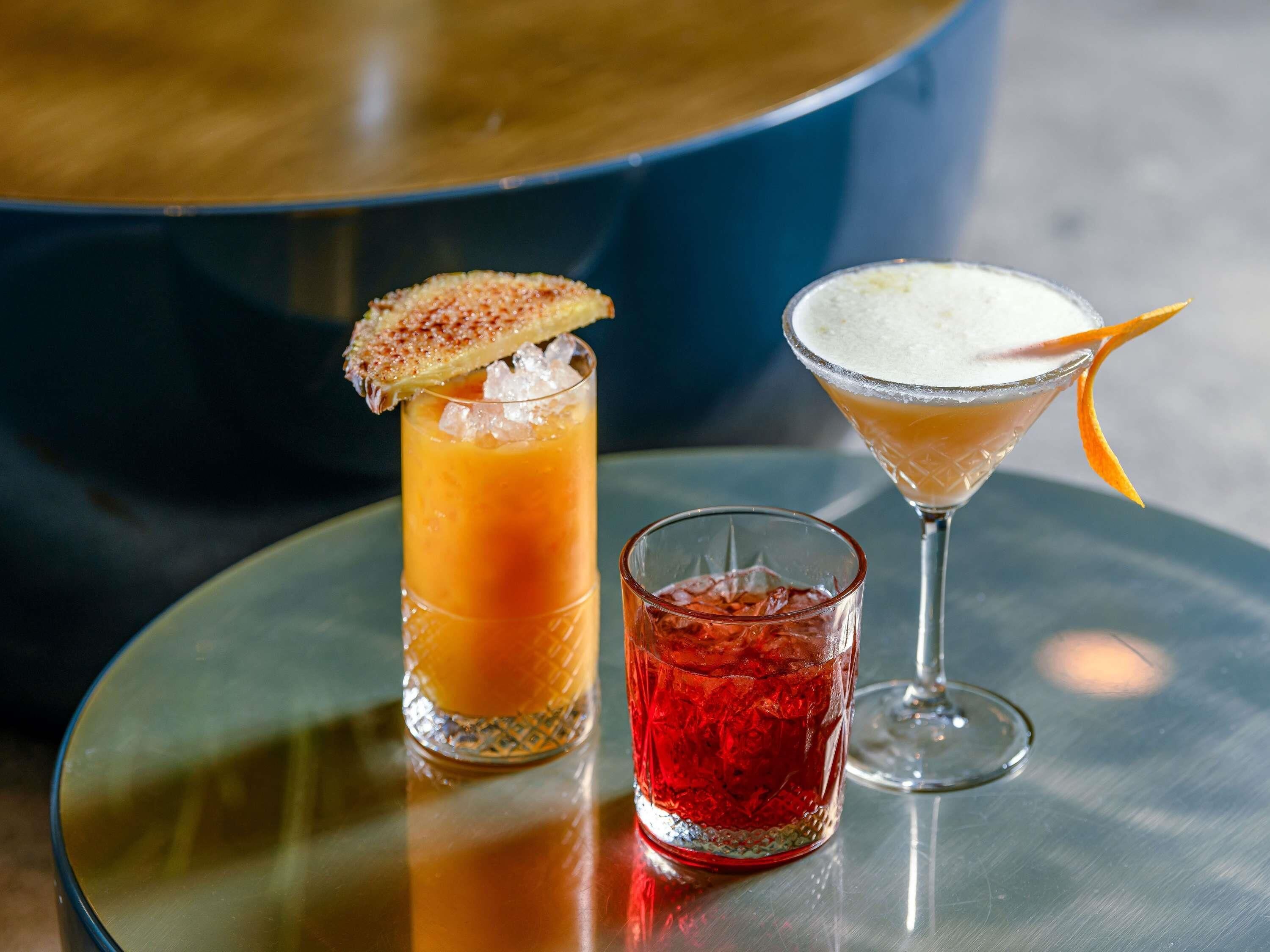Three drinks on a round glass table with a blue background.