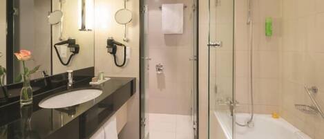 A modern bathroom with a glass-enclosed shower, a bathtub, and a vanity with a large mirror.