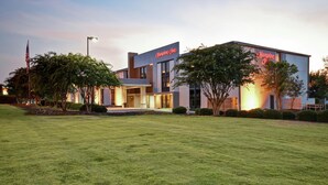 Un hotel moderno con techo plano, amplios ventanales y césped cuidado.