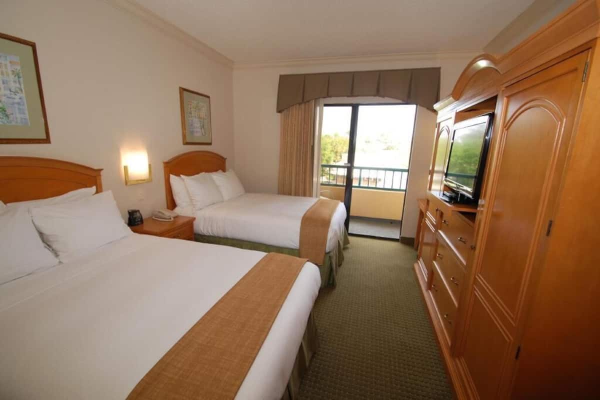 Une chambre d’hôtel avec deux lits, une télévision, un bureau et une fenêtre donnant sur un paysage agréable.