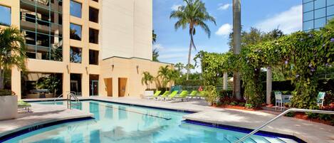 Una piscina al aire libre, sillones reclinables de piscina