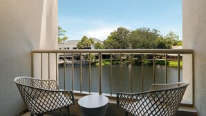 Ein Balkon mit zwei Stühlen und einem kleinen Tisch, der auf ein Gewässer und ein Gebäude mit der Aufschrift 'TERRACE' blickt.