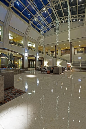 A spacious lobby with a high ceiling, a central staircase, and a seating area.