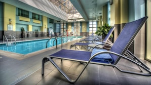 Una piscina interior con sillas de descanso y techo de cristal.