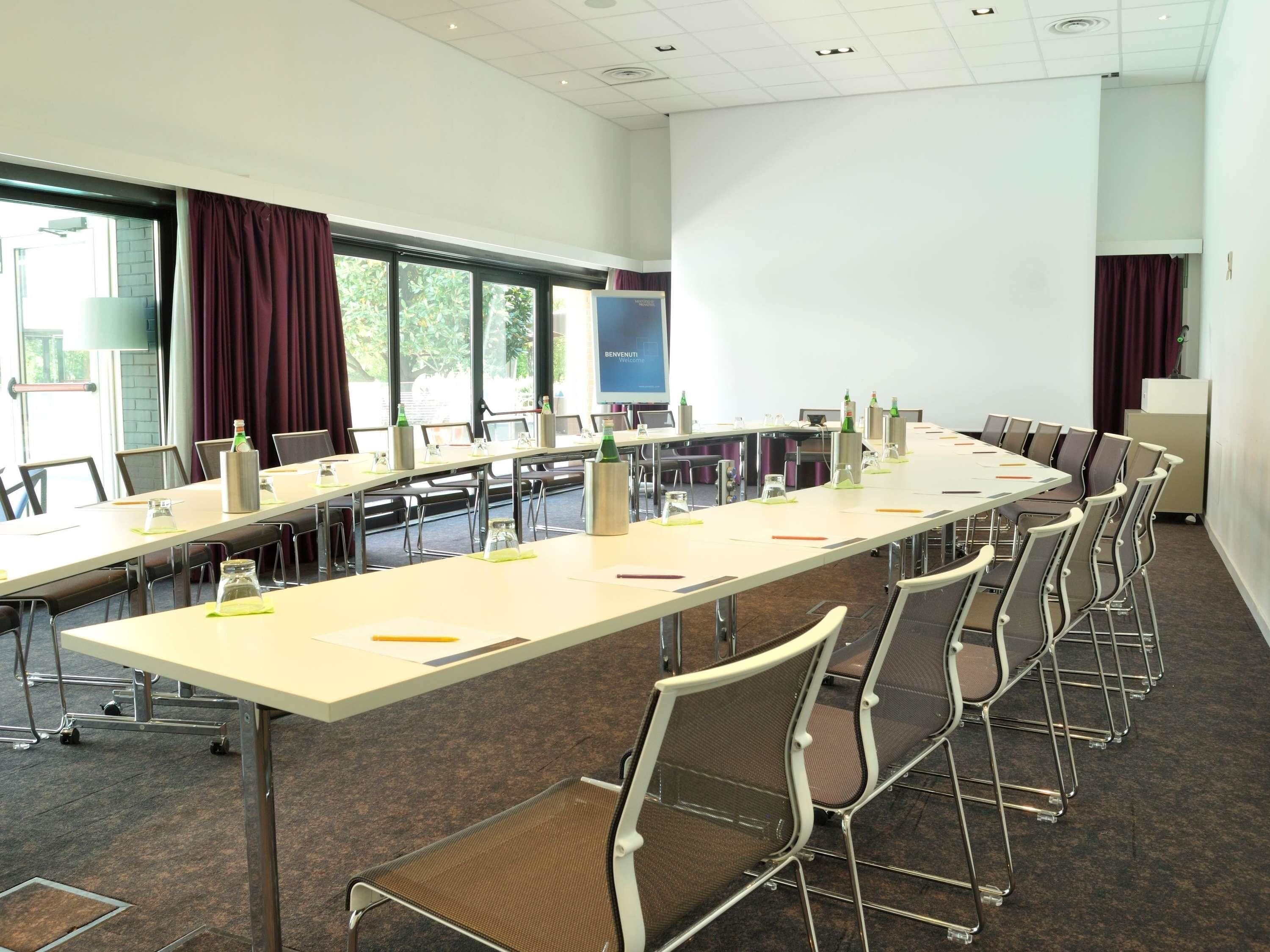 A conference room with a long table, chairs, a projector screen, and a whiteboard.