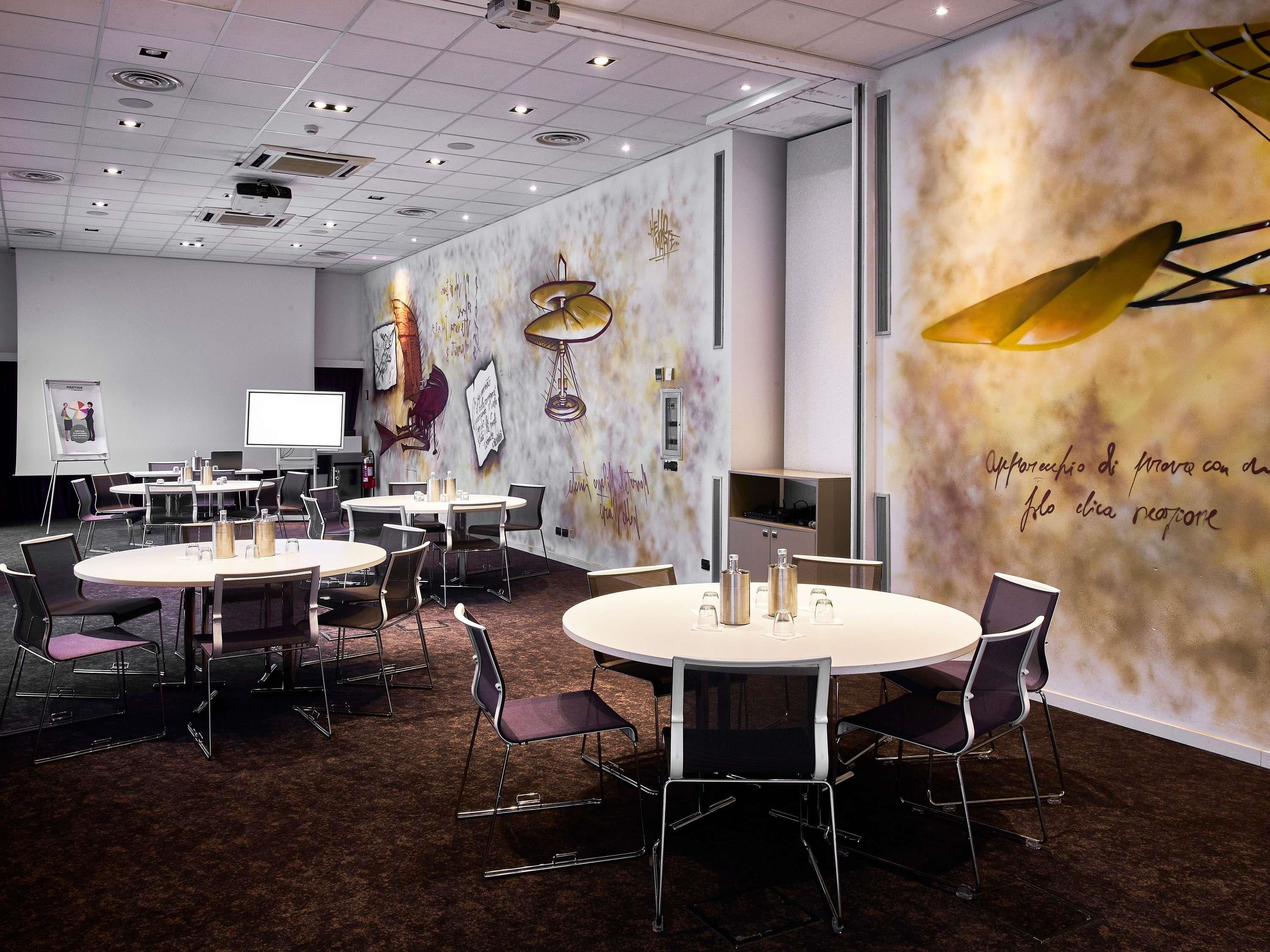 A conference room with round tables, chairs, a projector, and a whiteboard.