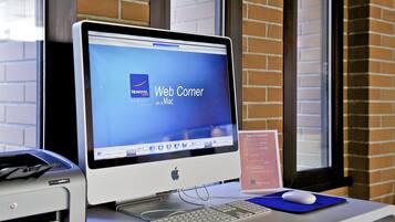 Een bureaubcomputer met een monitor waarop een website wordt weergegeven, een toetsenbord, een muis en een printer op een bureau.