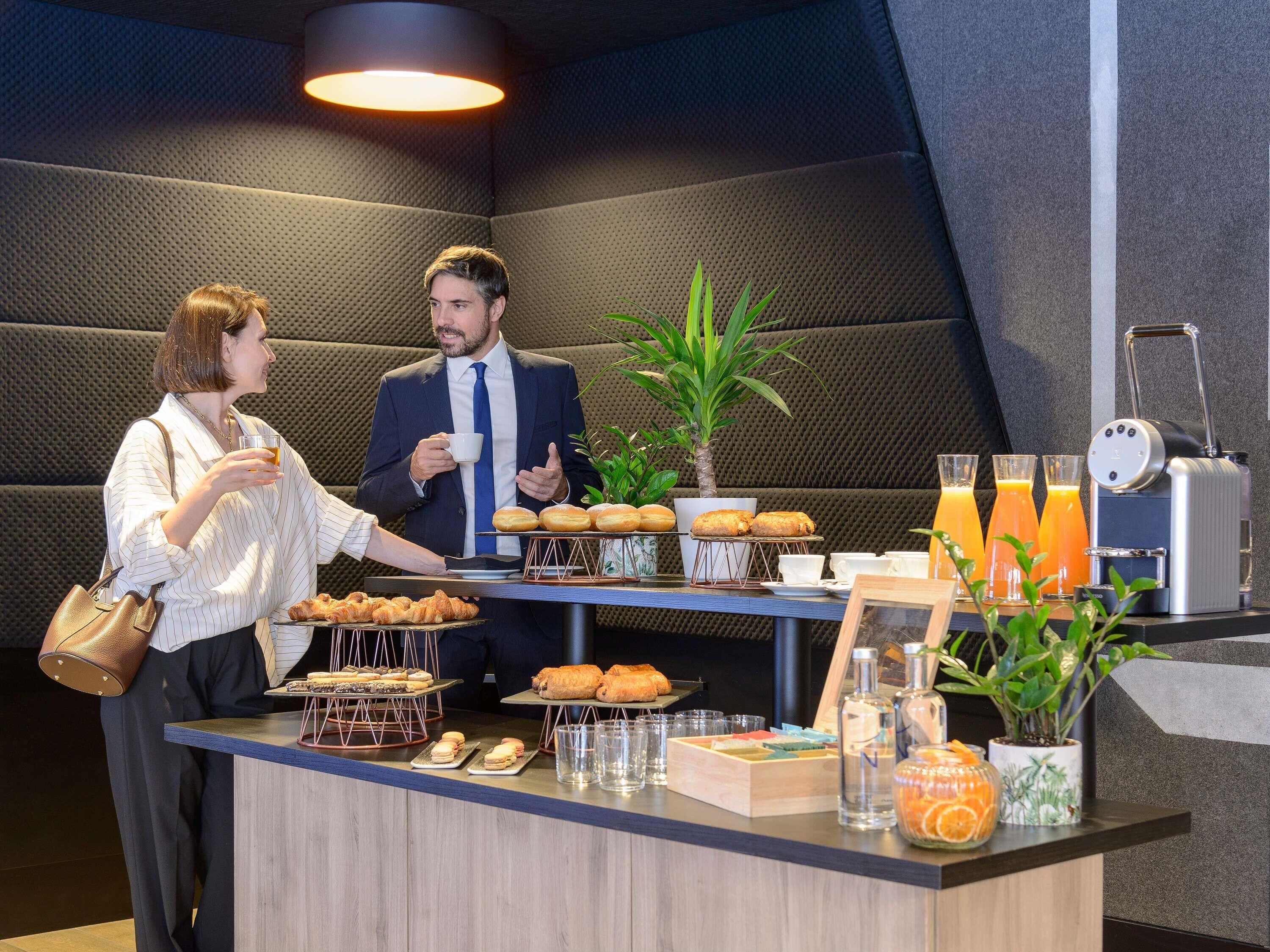 A breakfast buffet with pastries, a coffee machine, and a plant.