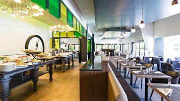 Un comedor moderno con barra libre, diferentes disposiciones de mesas y vistas al exterior.