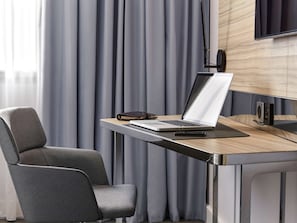 Work and unwind in a clean, contemporary space with a desk, flat-screen TV, and comfortable armchair.