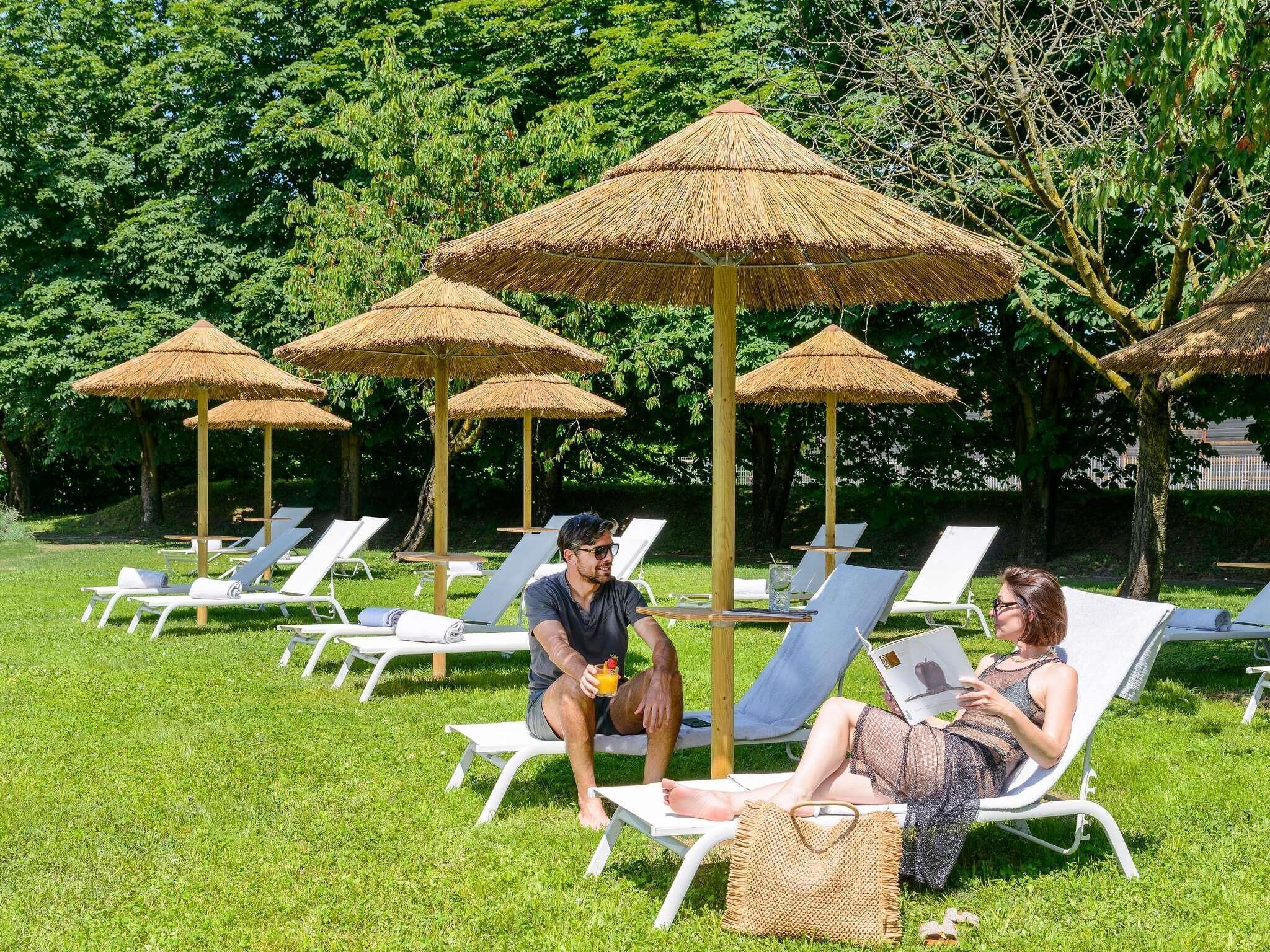 Een tuin met loungezetels en rieten parasols.