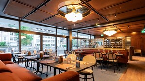 Ein modernes Restaurant mit großen Fenstern, Holzmöbeln und einer Bar.