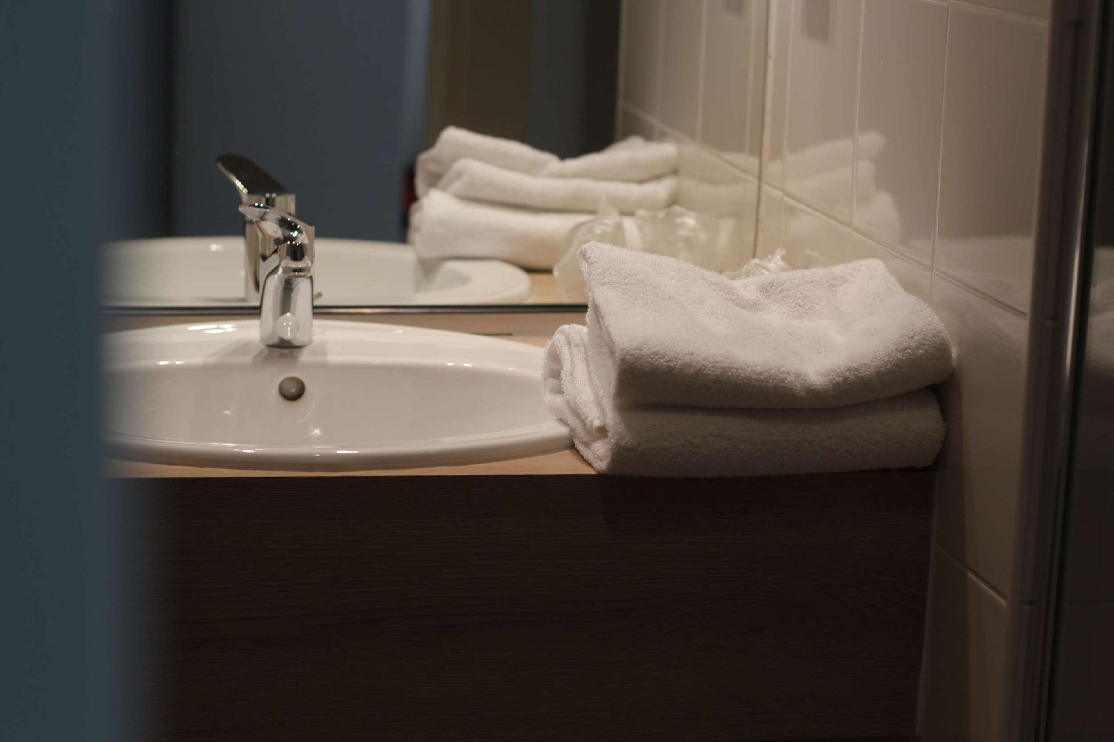 Une salle de bain avec un lavabo, un miroir et des serviettes pliées.