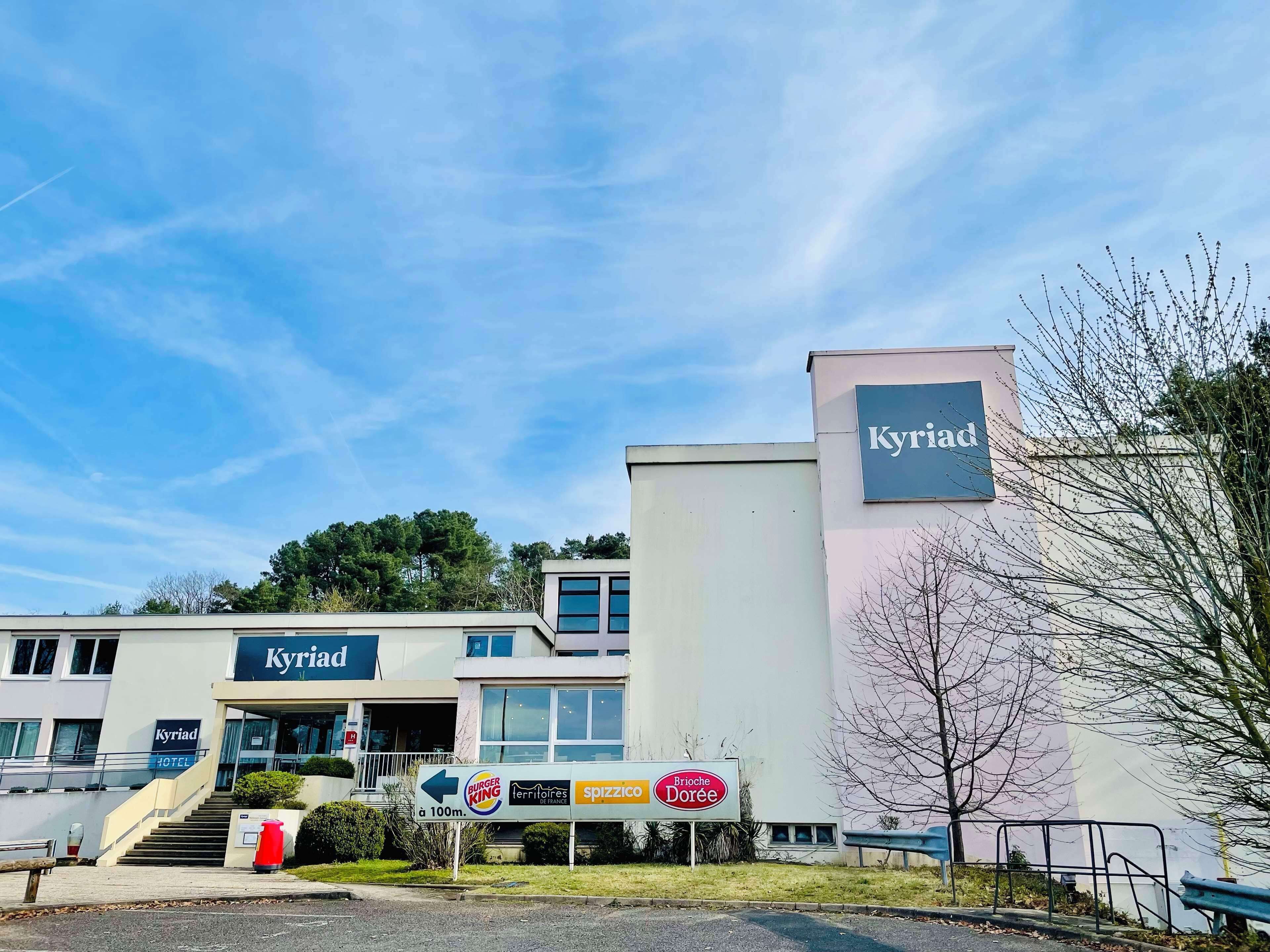 Un hôtel appelé « Kyriad », avec une enseigne indiquant qu’il se trouve à 100 mètres de Burger King, Spizzico et Brioches Dorée.