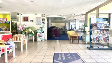 A reception area with a welcome mat, plush toys, a seating area, and a magazine rack.