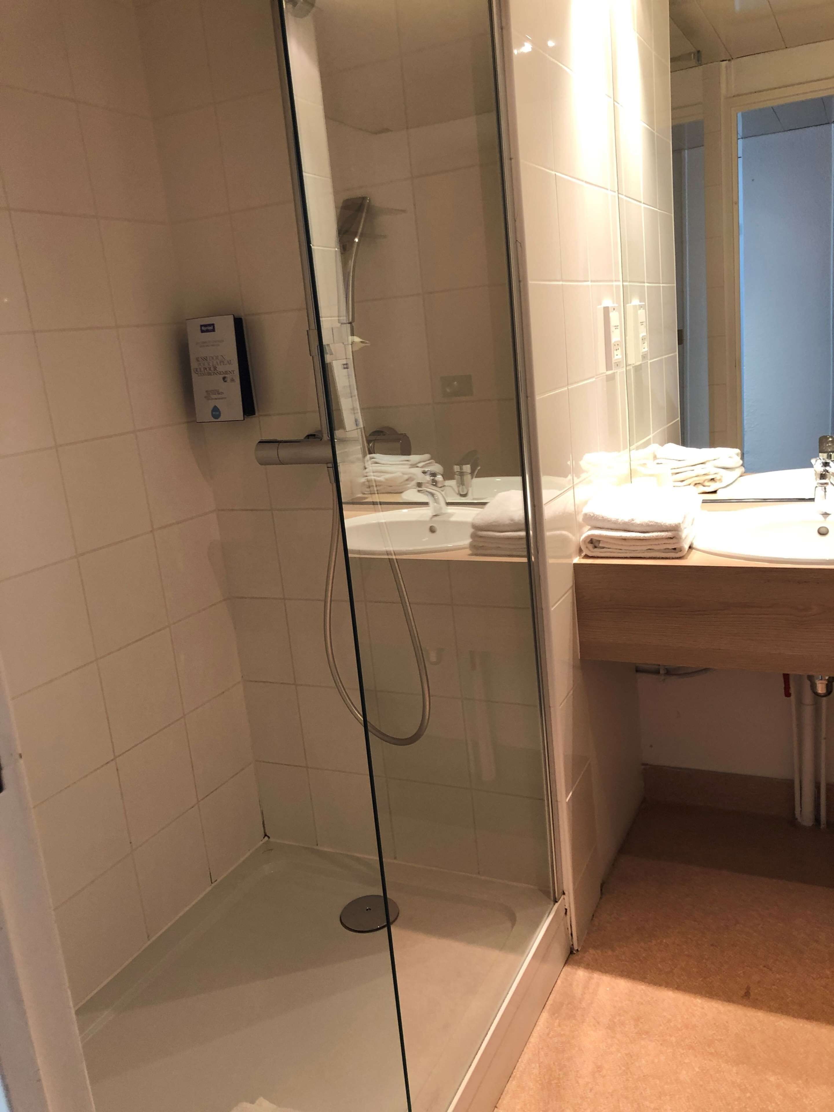 Une salle de bain moderne avec une douche à parois de verre, un lavabo et un miroir.