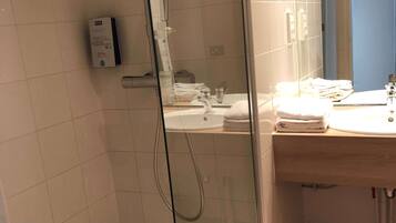 Une salle de bain moderne avec une douche à parois de verre, un lavabo et un miroir.