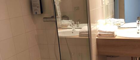Un baño moderno con ducha de vidrio, lavamanos y espejo.