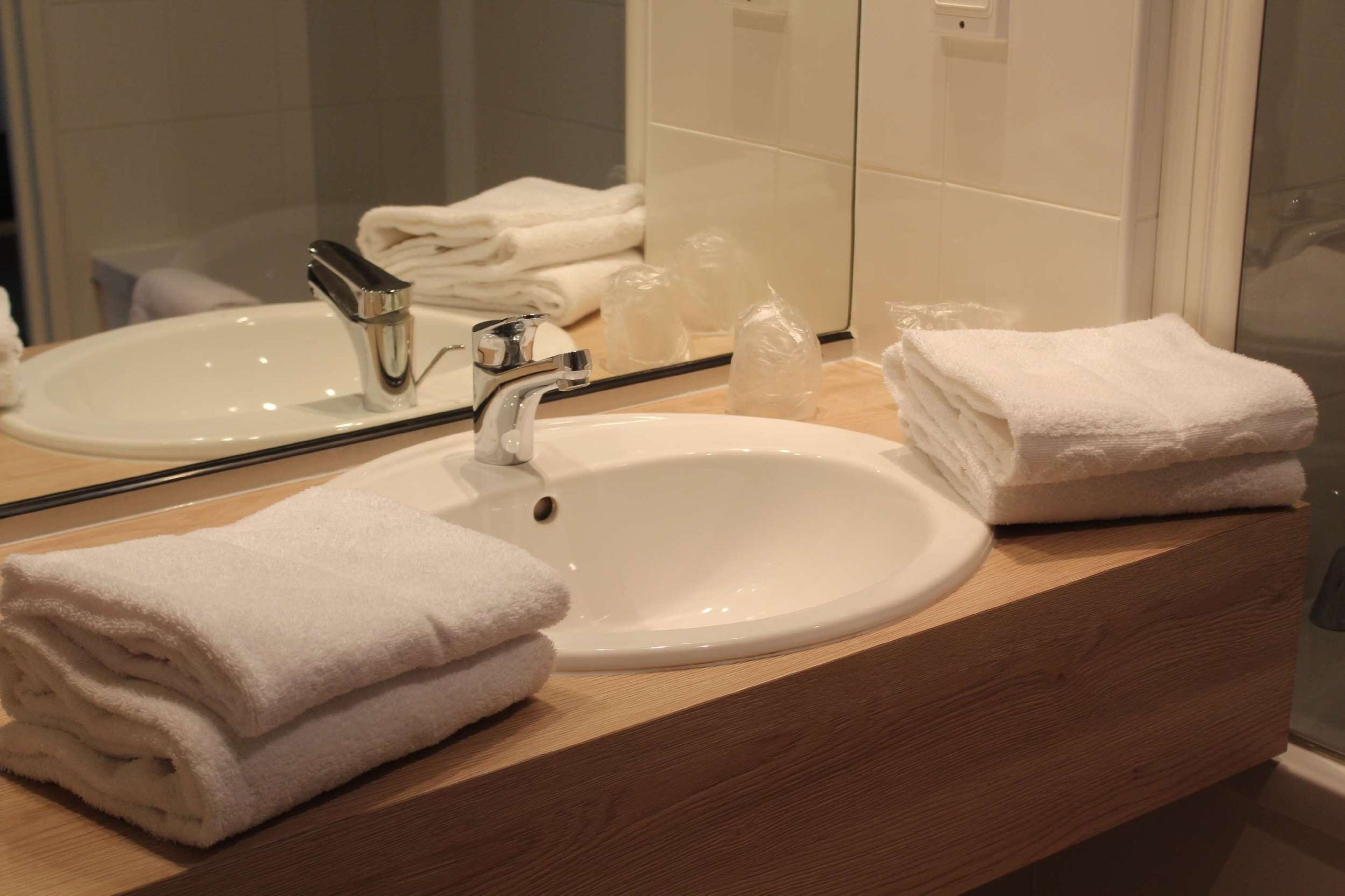 A bathroom with a white sink, a mirror, and a wooden vanity.